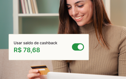 Imagem de uma mulher olhando o cartão com o valor do saldo disponível para utilizar de cashback