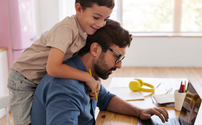 Uma pessoa trabalhando do notebook junto ao filho